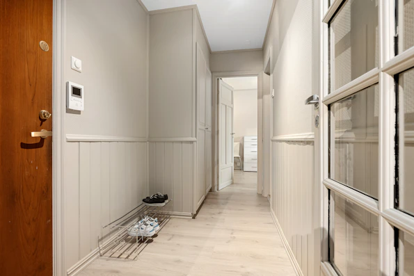A hallway with a wooden door and a pair of shoes on the floor
