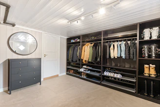 A walk in closet with a mirror and a clock