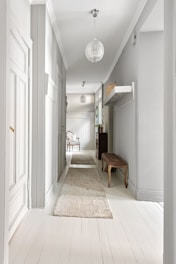 A long hallway with white walls and wooden floors