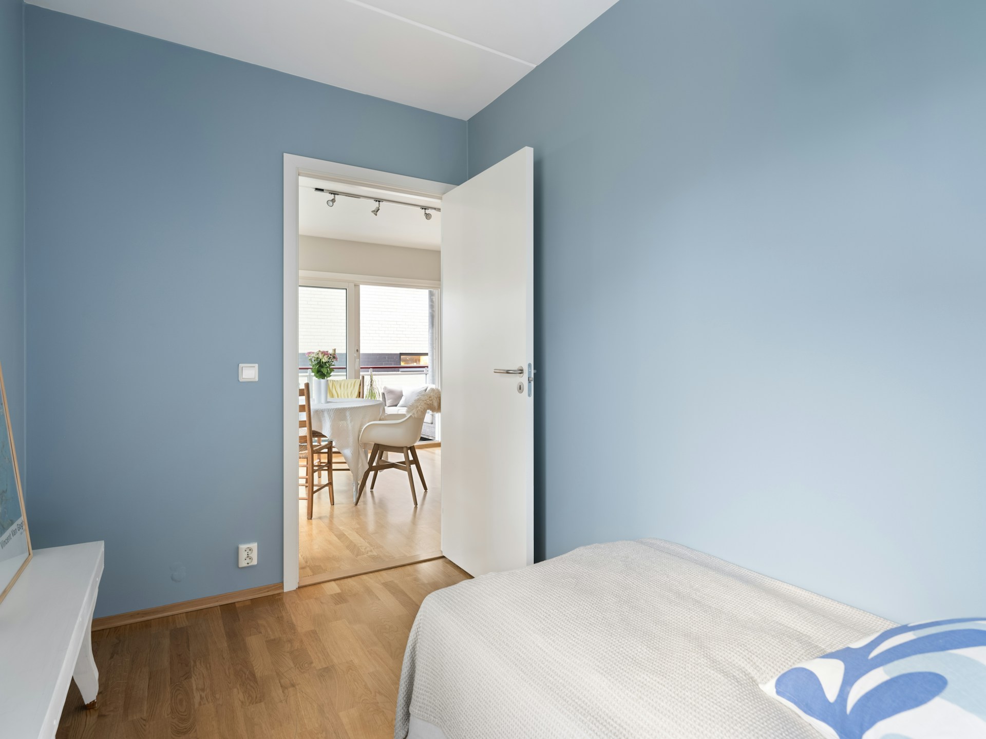A bedroom with blue walls and a white bed