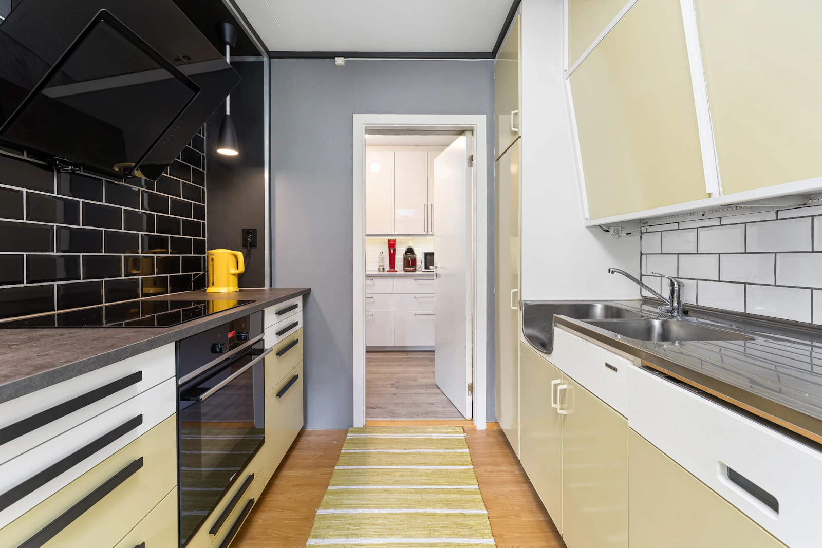 Narrow kitchen combining yellow lower cabinetry with white upper cabinets and pale walls