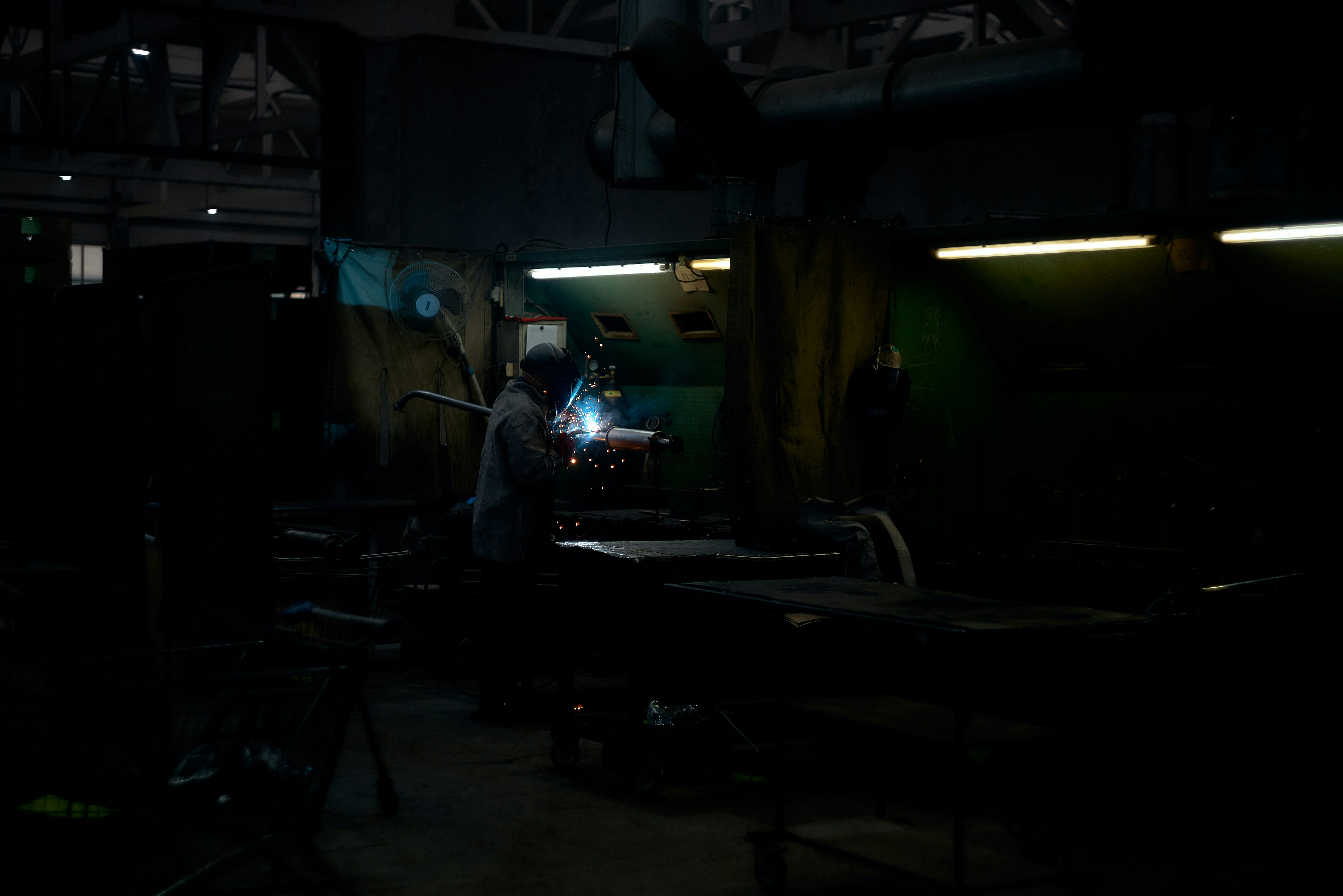 Emergency industrial repair crew working under bright lights in a dark warehouse, urgent atmosphere, steel equipment