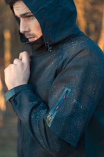 A man in a hooded jacket standing in the woods