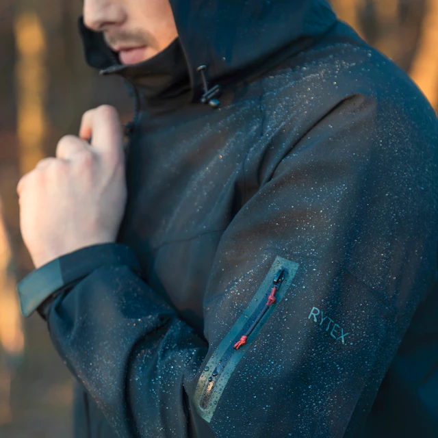 A man in a hooded jacket standing in the woods