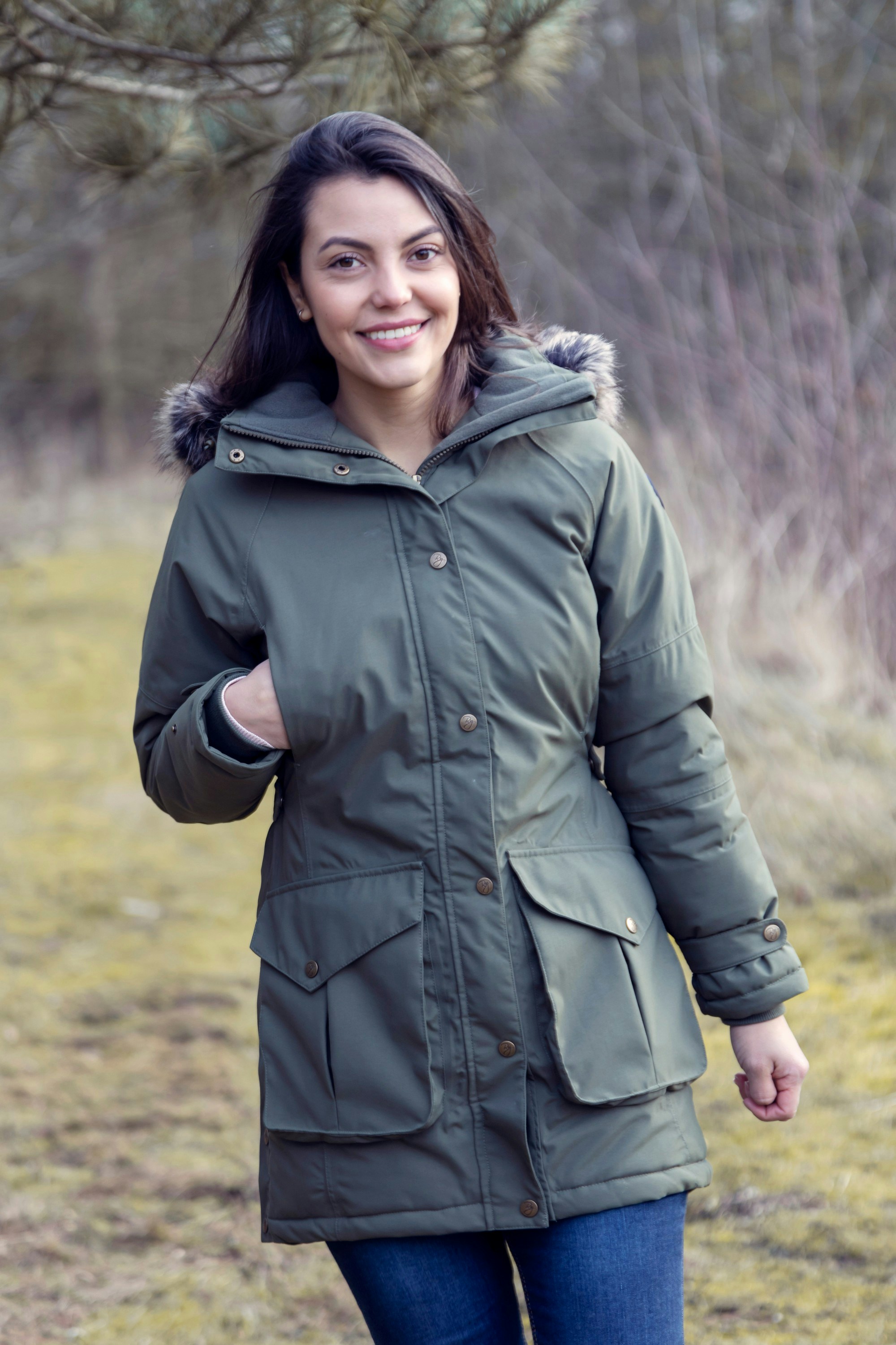 A woman in a green parka walking in the woods