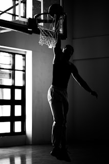 A man dunking a basketball in a gym