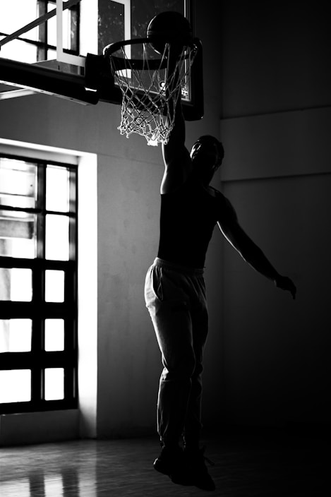 A man dunking a basketball in a gym