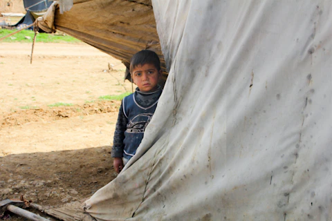 A young boy standing in front of a tent