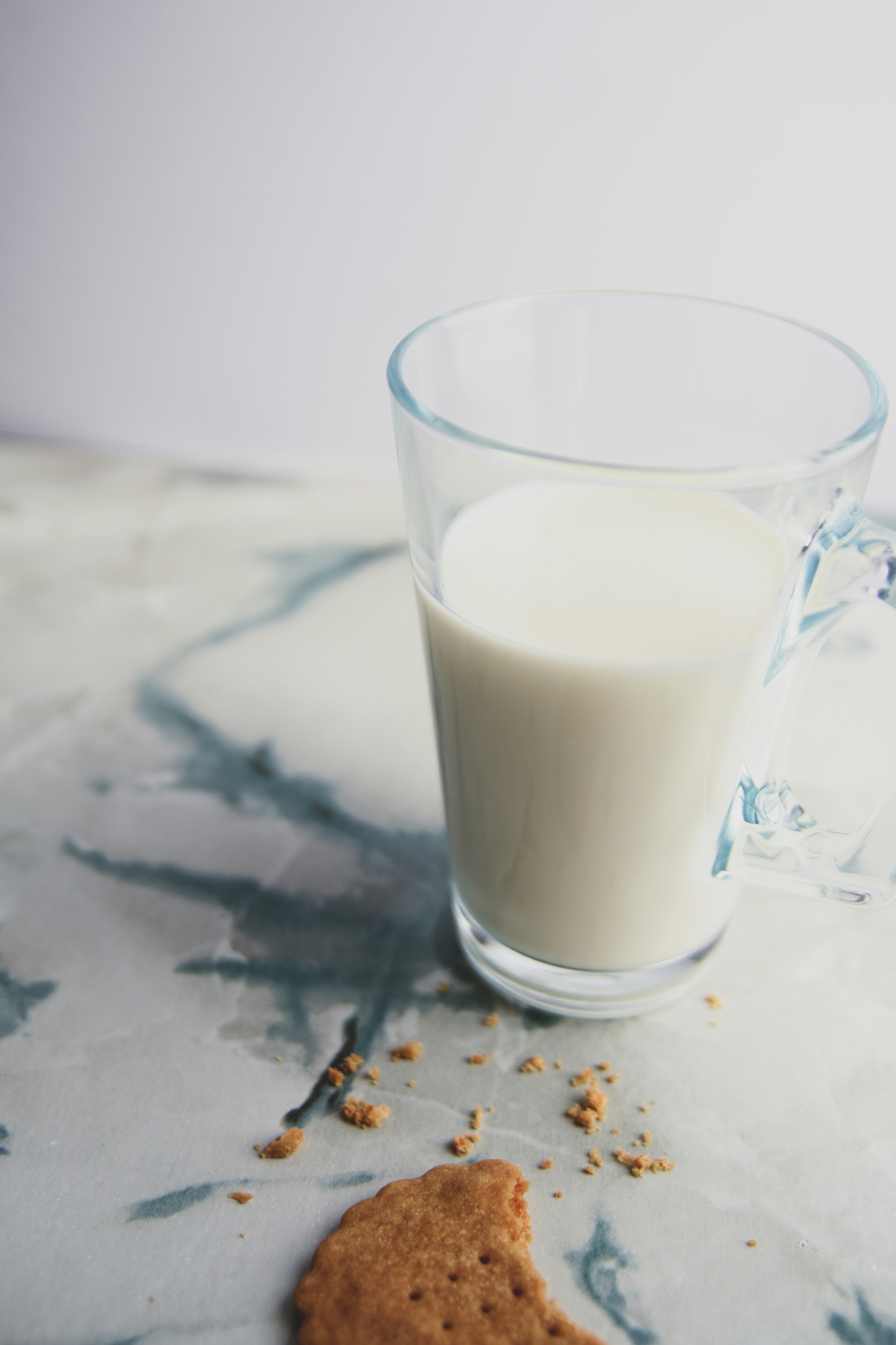 A cookie and a glass of milk on a marble table