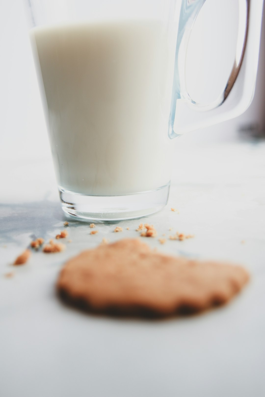 A cookie next to a glass of milk