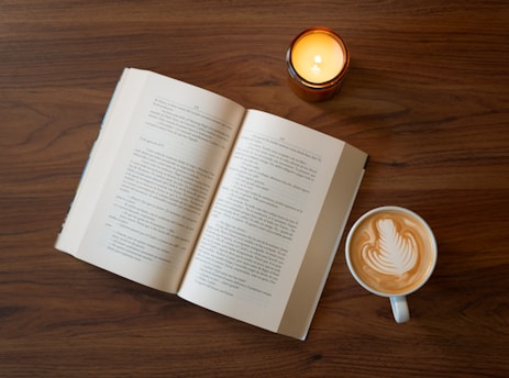 A cup of coffee and an open book on a table