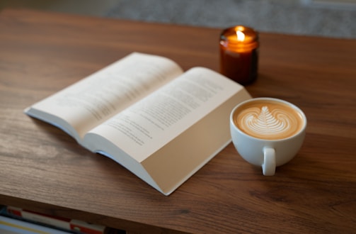 A cup of coffee and an open book on a table