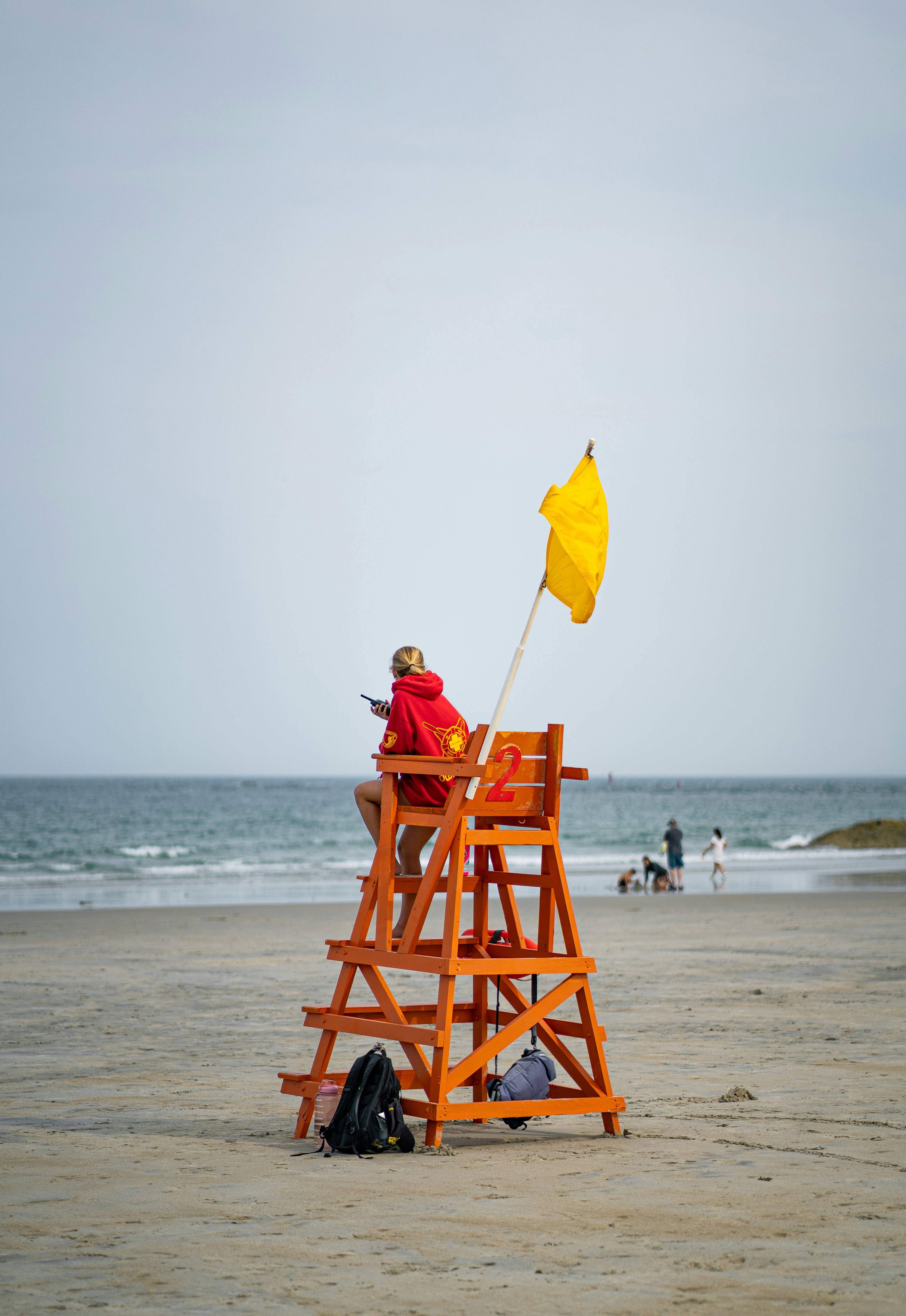 A lifeguard chair on the beach with a yellow flag