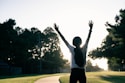 A person standing on a road with their arms in the air