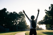 A person standing on a road with their arms in the air