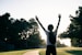 A person standing on a road with their arms in the air