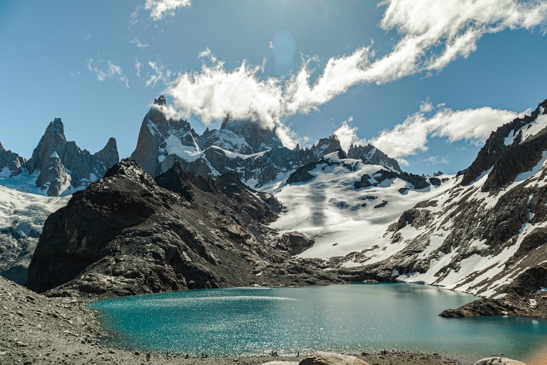A person taking a picture of a mountain lake, Cloudy Fitz Roy