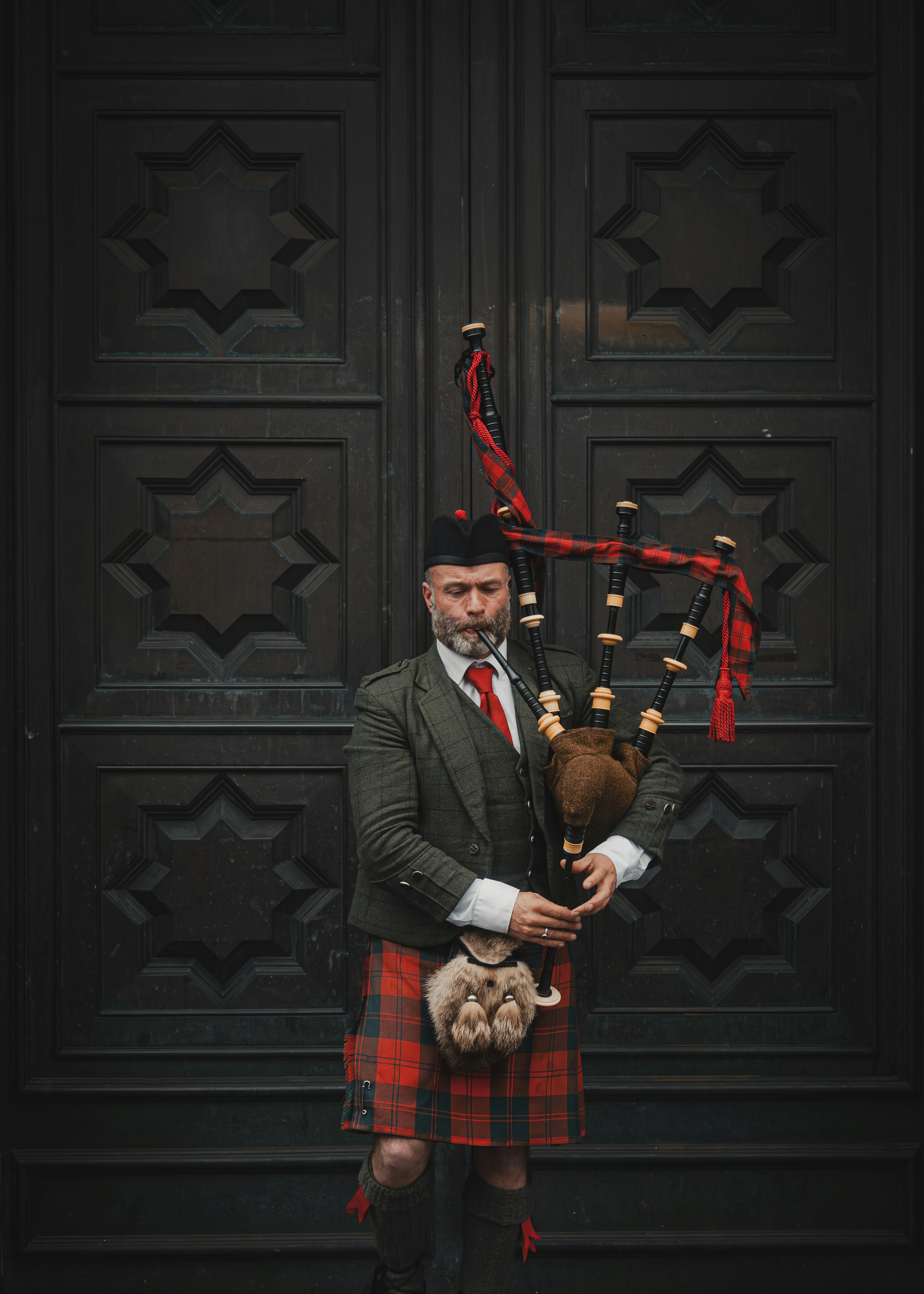 A man in a kilt holding a teddy bear