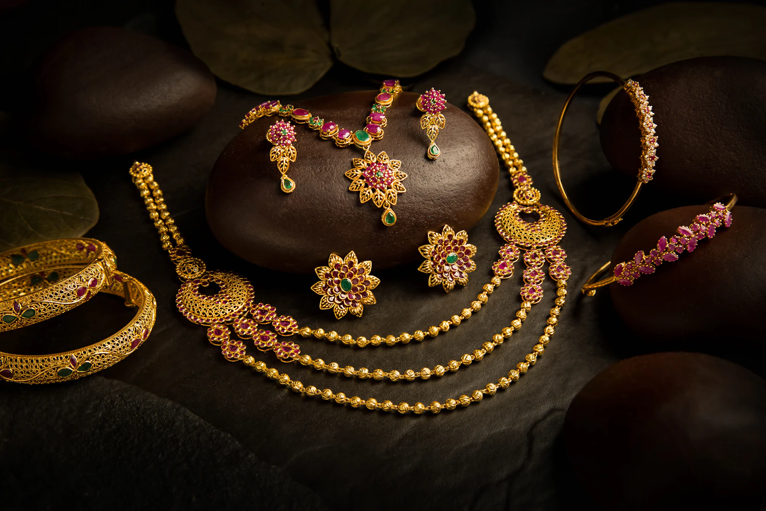 Handcrafted gold jewellery arranged on a dark table