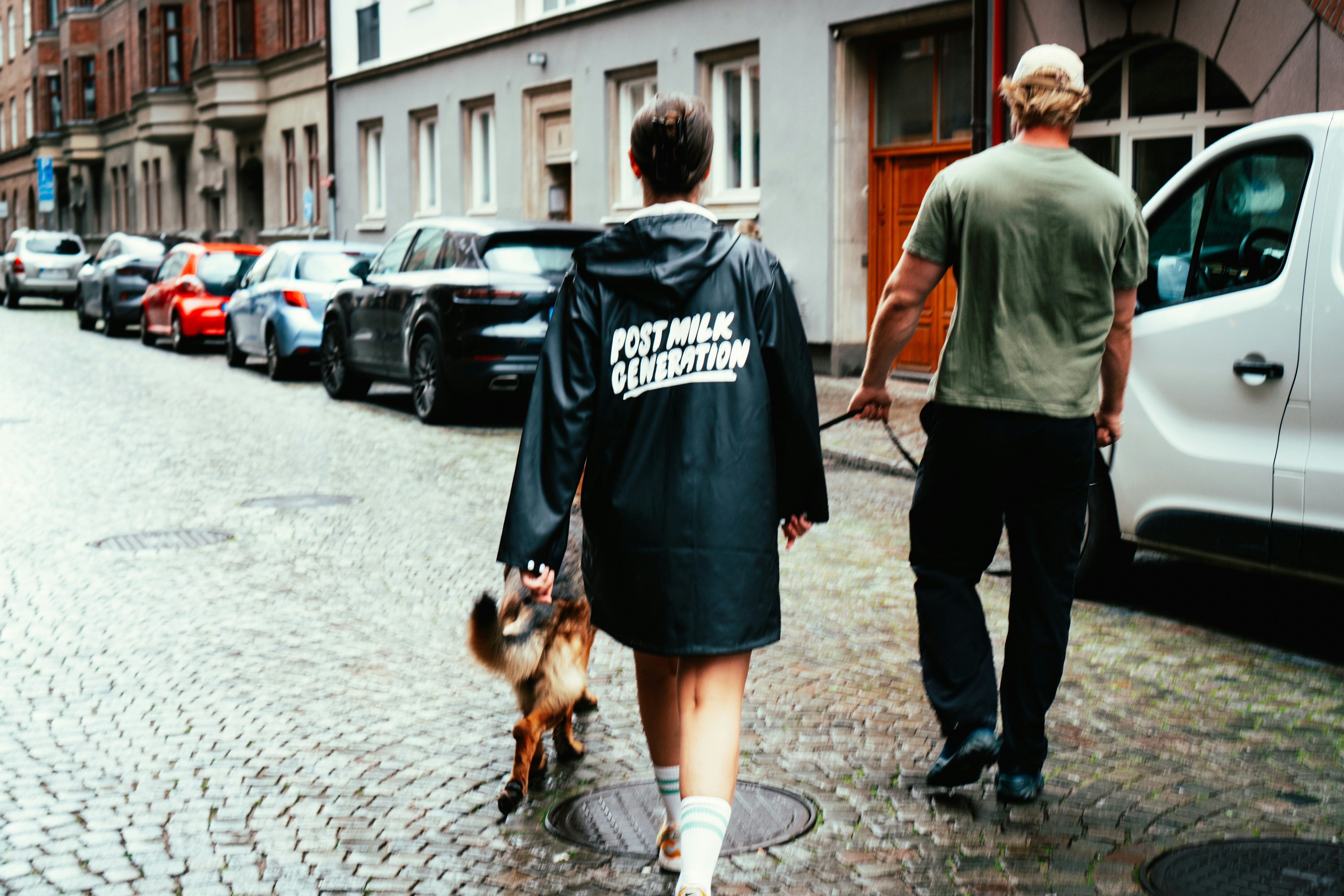 A man and a woman walking a dog down a street