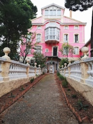 A pink house with a white fence and trees