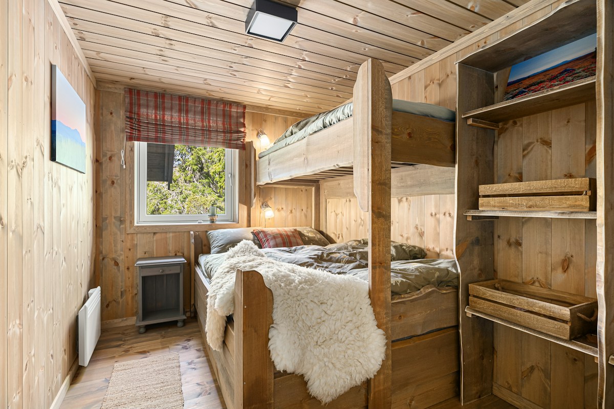 A bedroom with wooden bunk beds and a window, ideal for youth retreat lodging and planning accommodations.