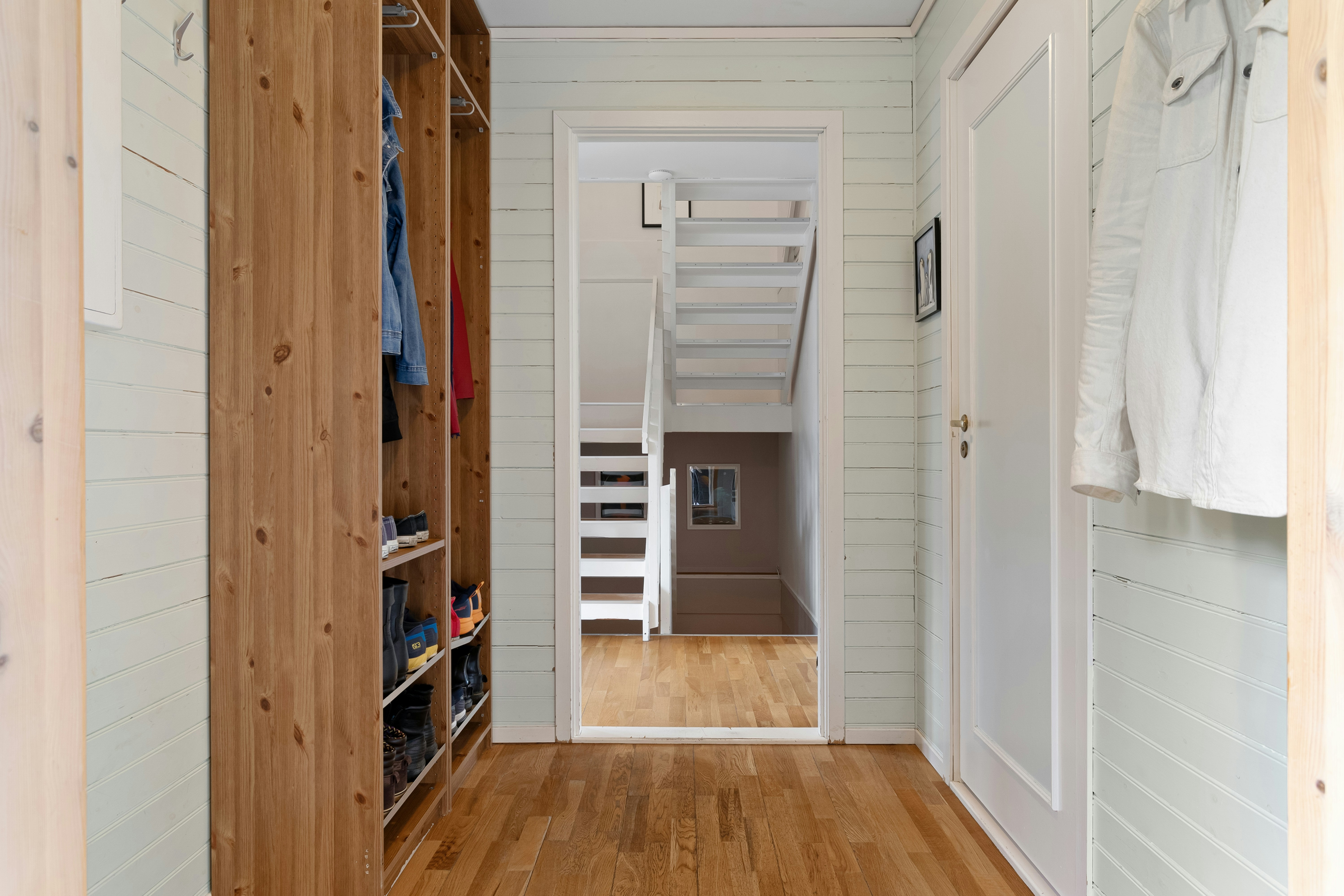 A narrow hallway with a wooden floor and white walls