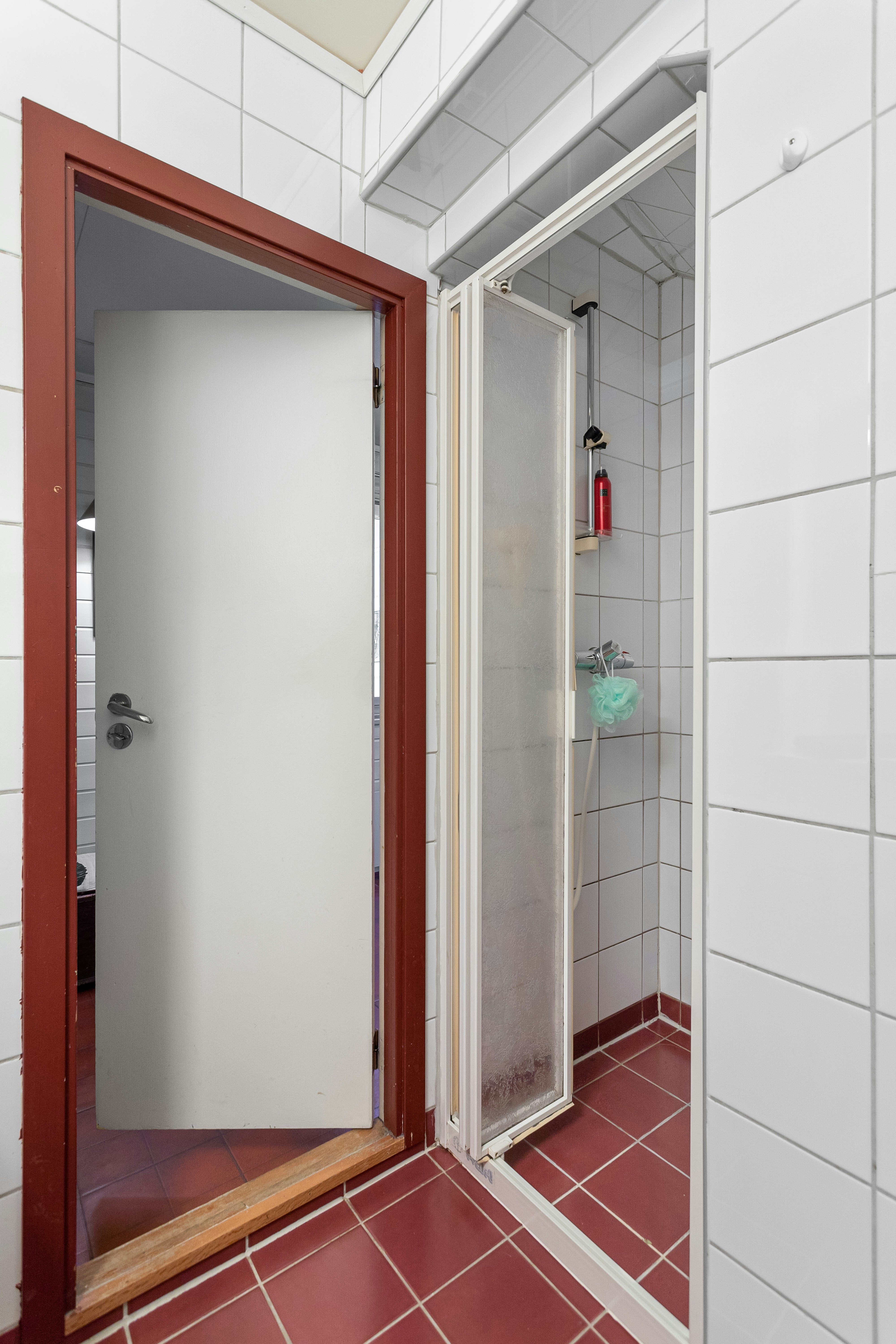 A bathroom with a red tile floor and white walls