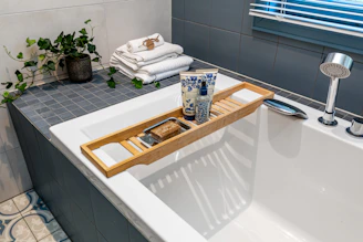 A bathtub with a tray of towels and a bottle of water