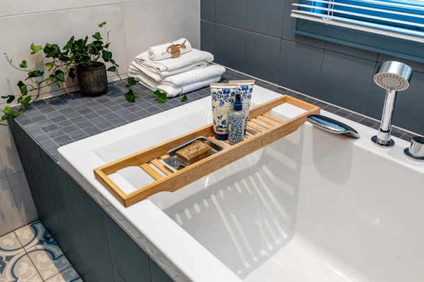 A bathtub with a tray of towels and a bottle of water