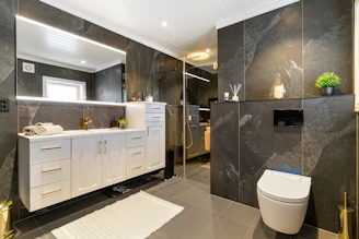 A bathroom with a toilet, sink, and mirror