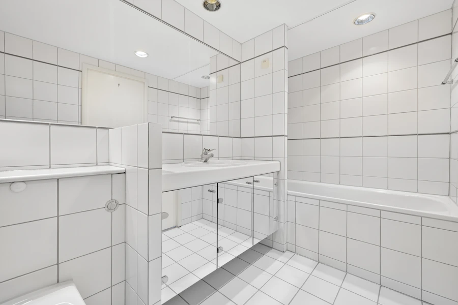 White tiled bathroom with a sink and toilet
