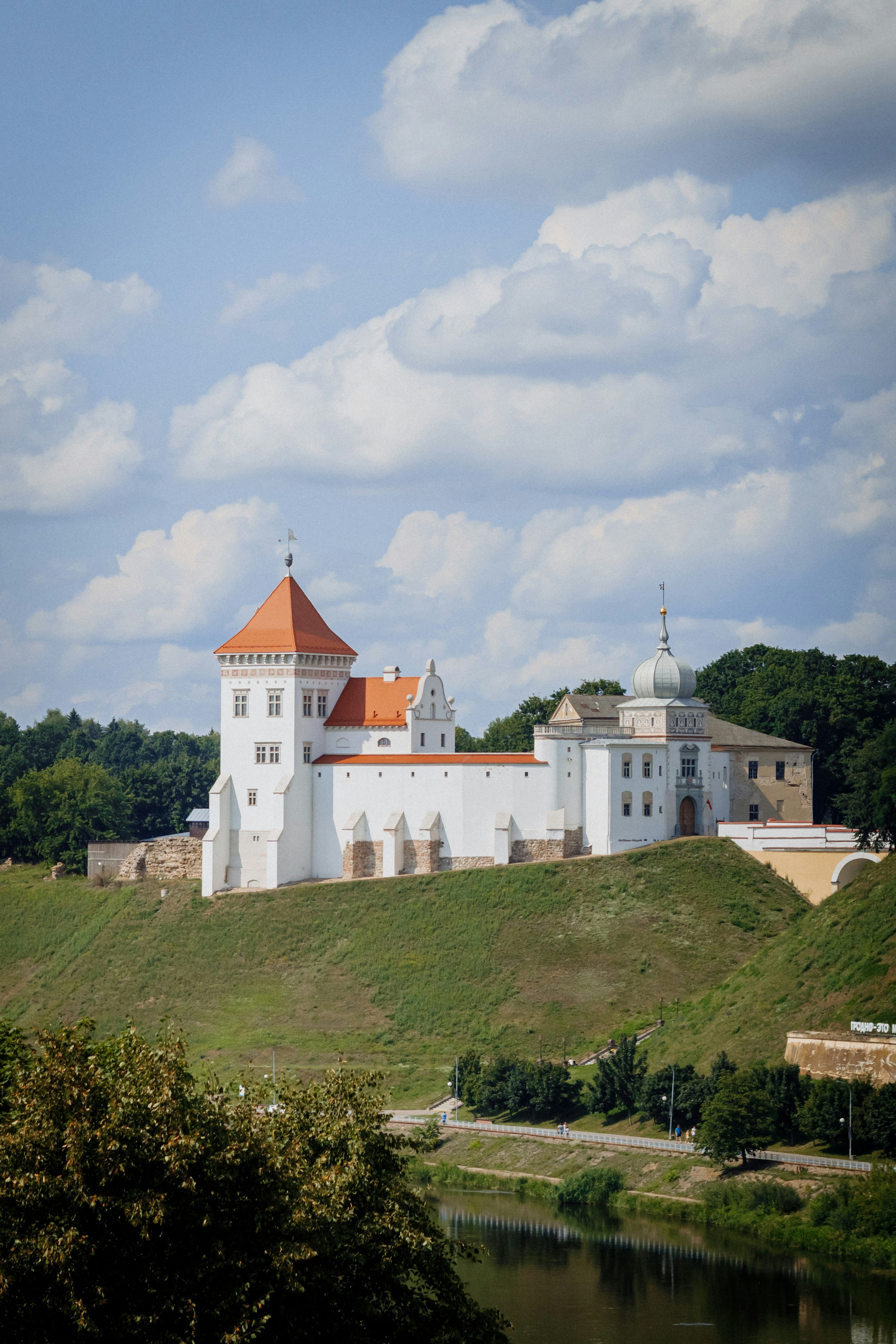 A large white building sitting on top of a lush green hillside