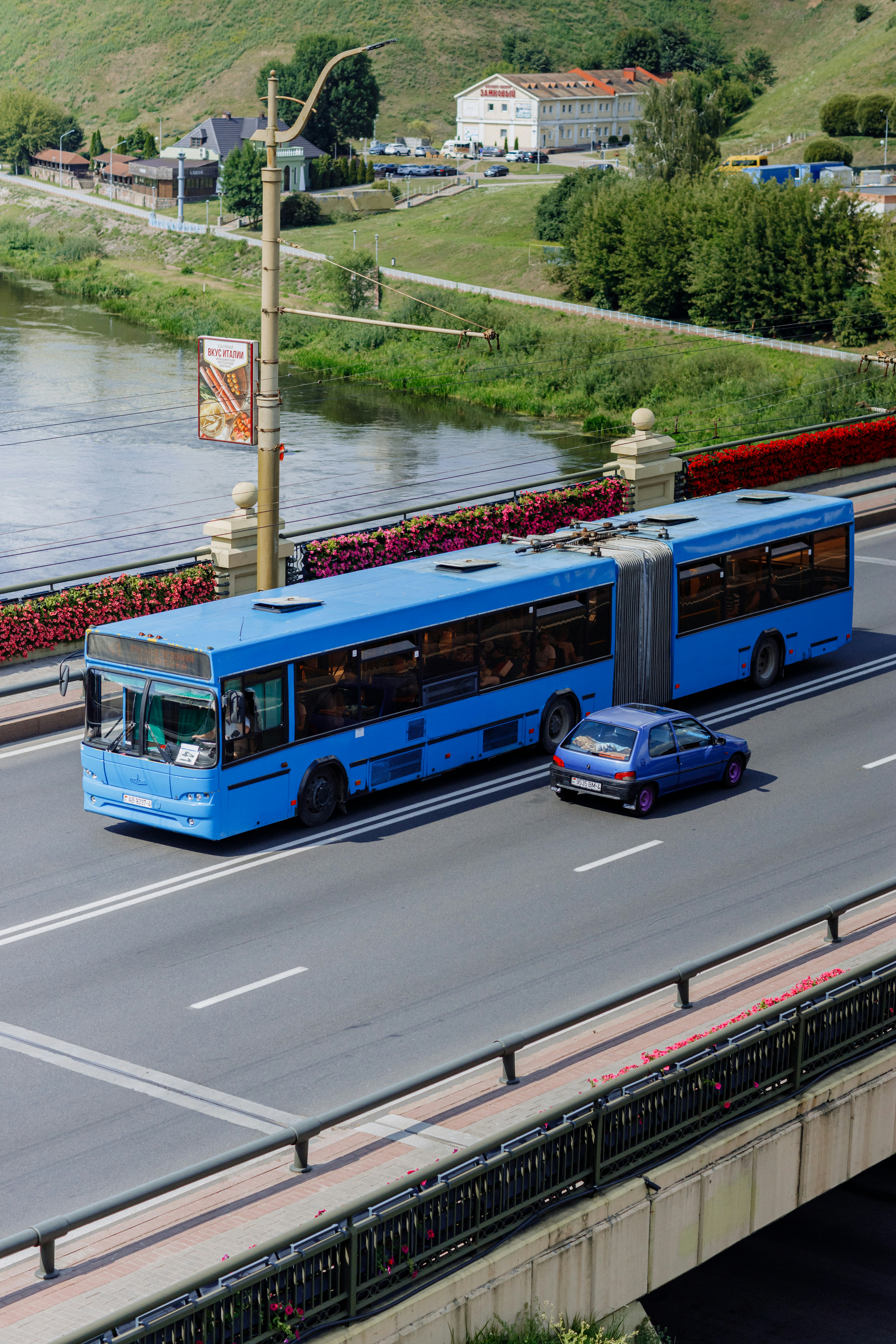 A blue bus driving down a street next to a river