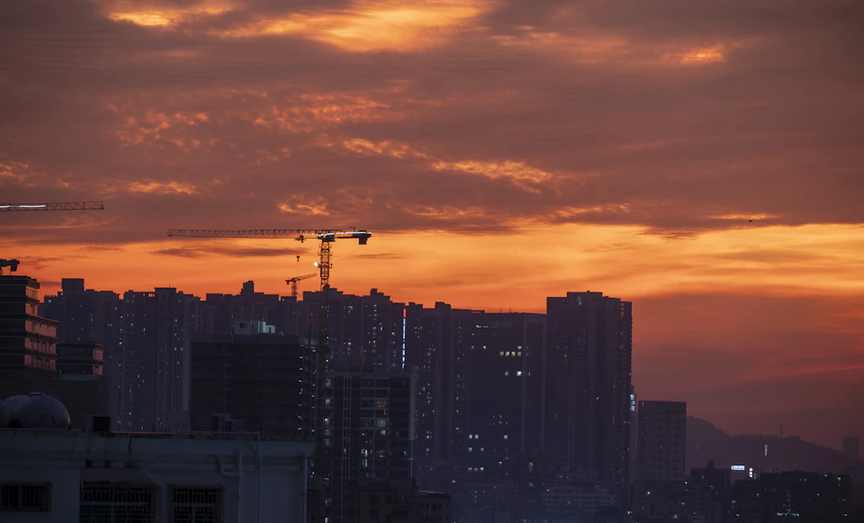 City skyline at sunset with orange and red hues, sun setting behind buildings