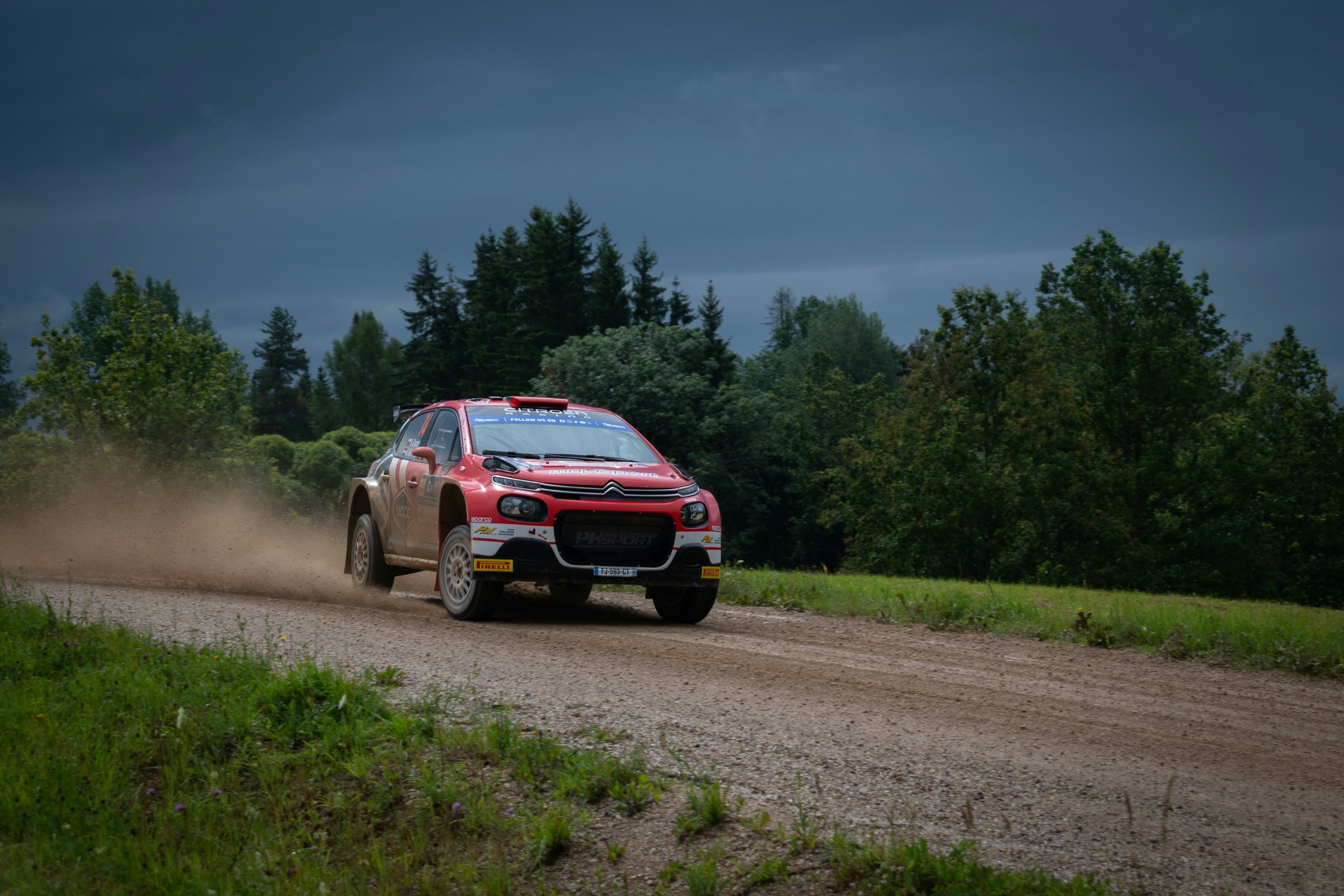 A red and white car driving down a dirt road