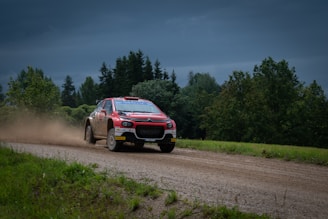 A red and white car driving down a dirt road