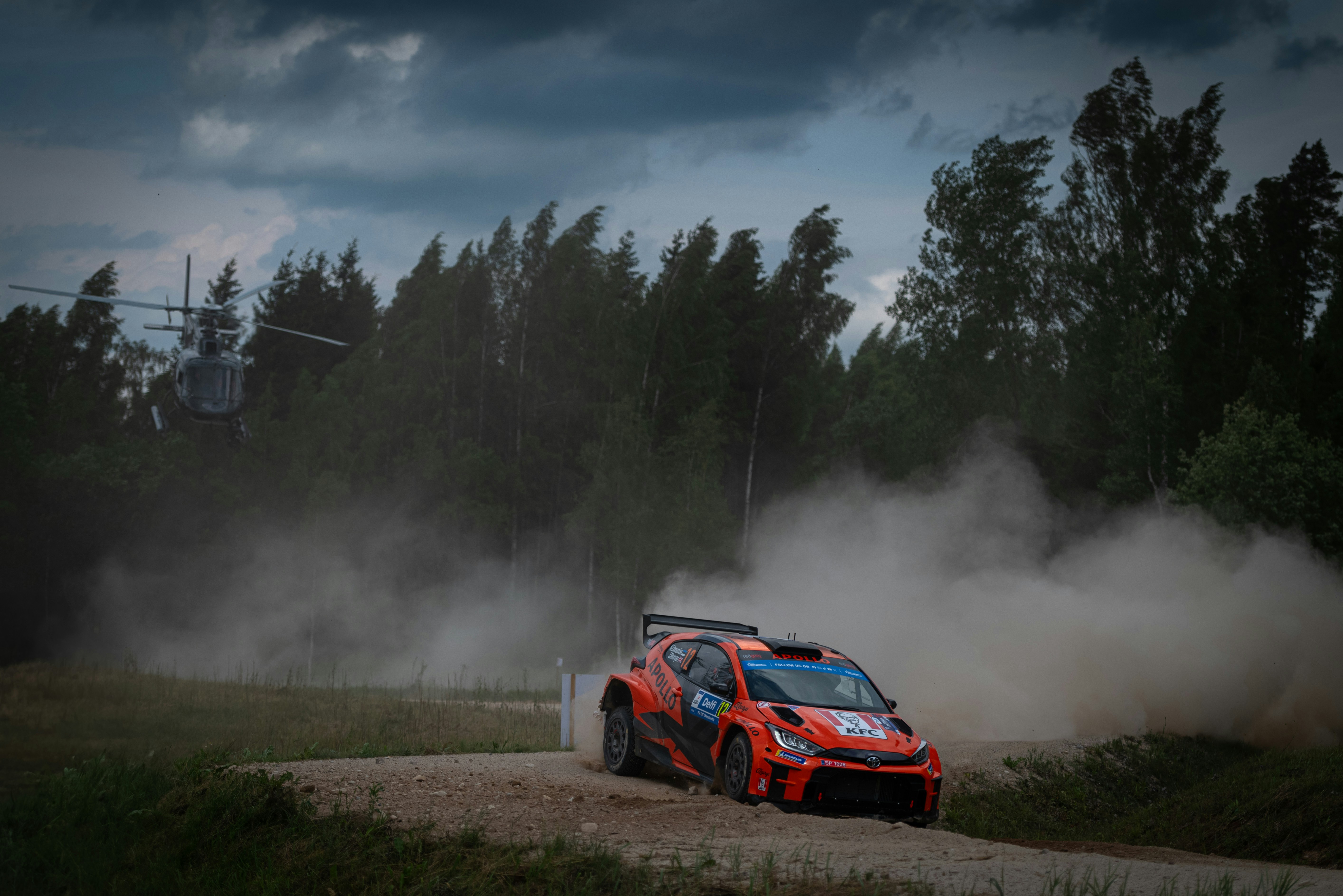 A car driving down a dirt road with trees in the background