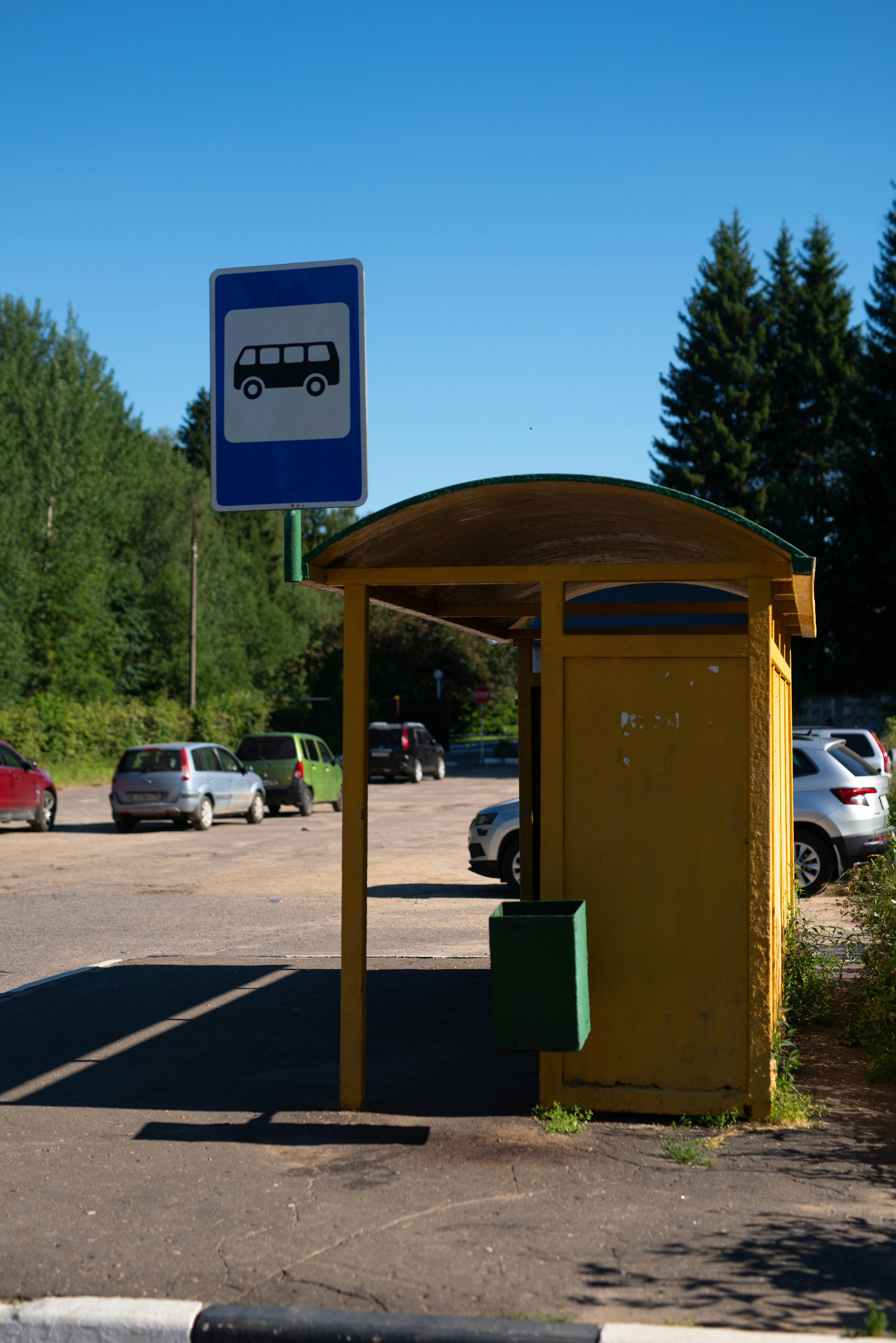 A bus stop with cars parked in a parking lot photo – Free Car Image on ...