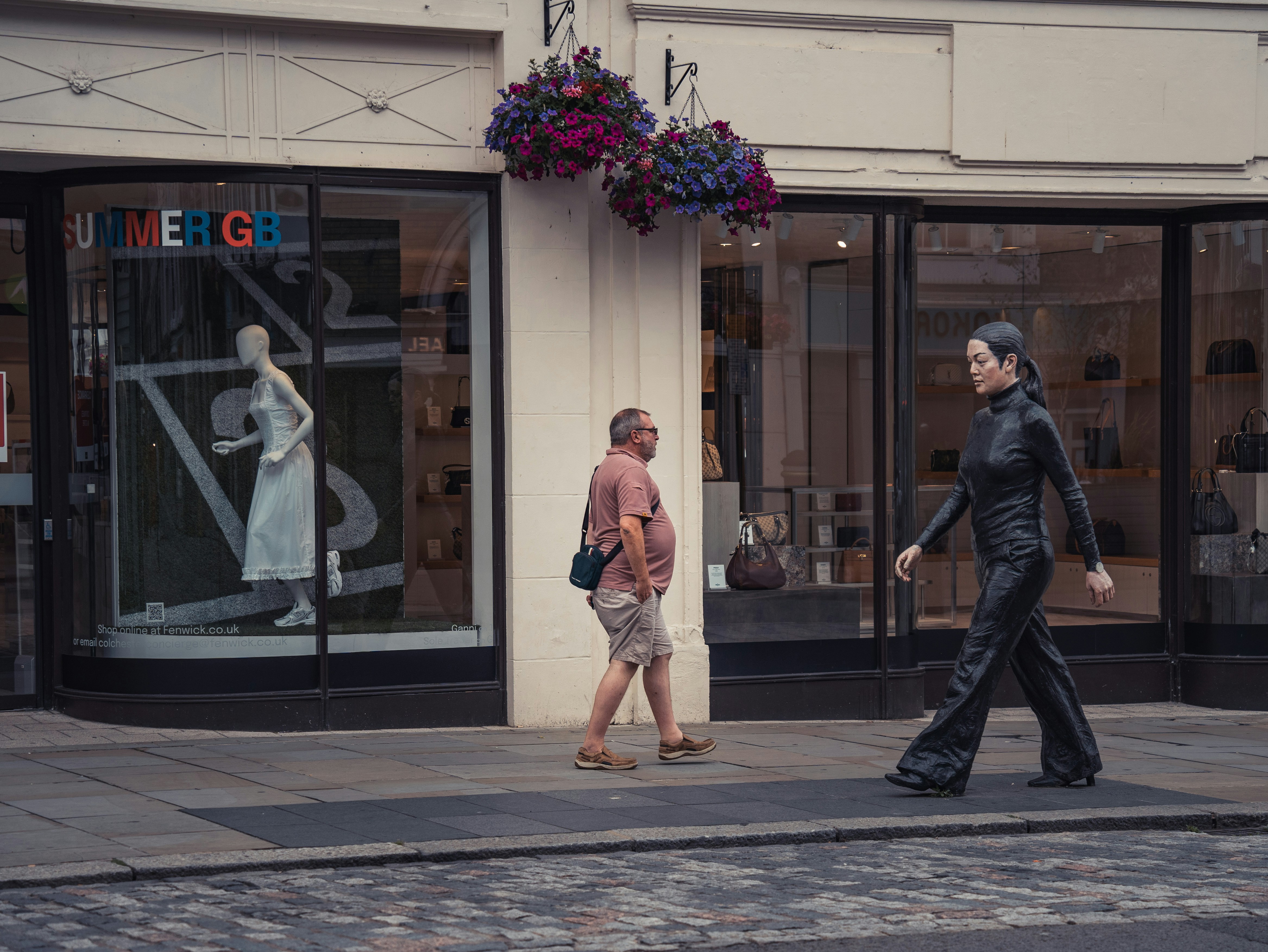 A couple of people walking down a street next to a tall building