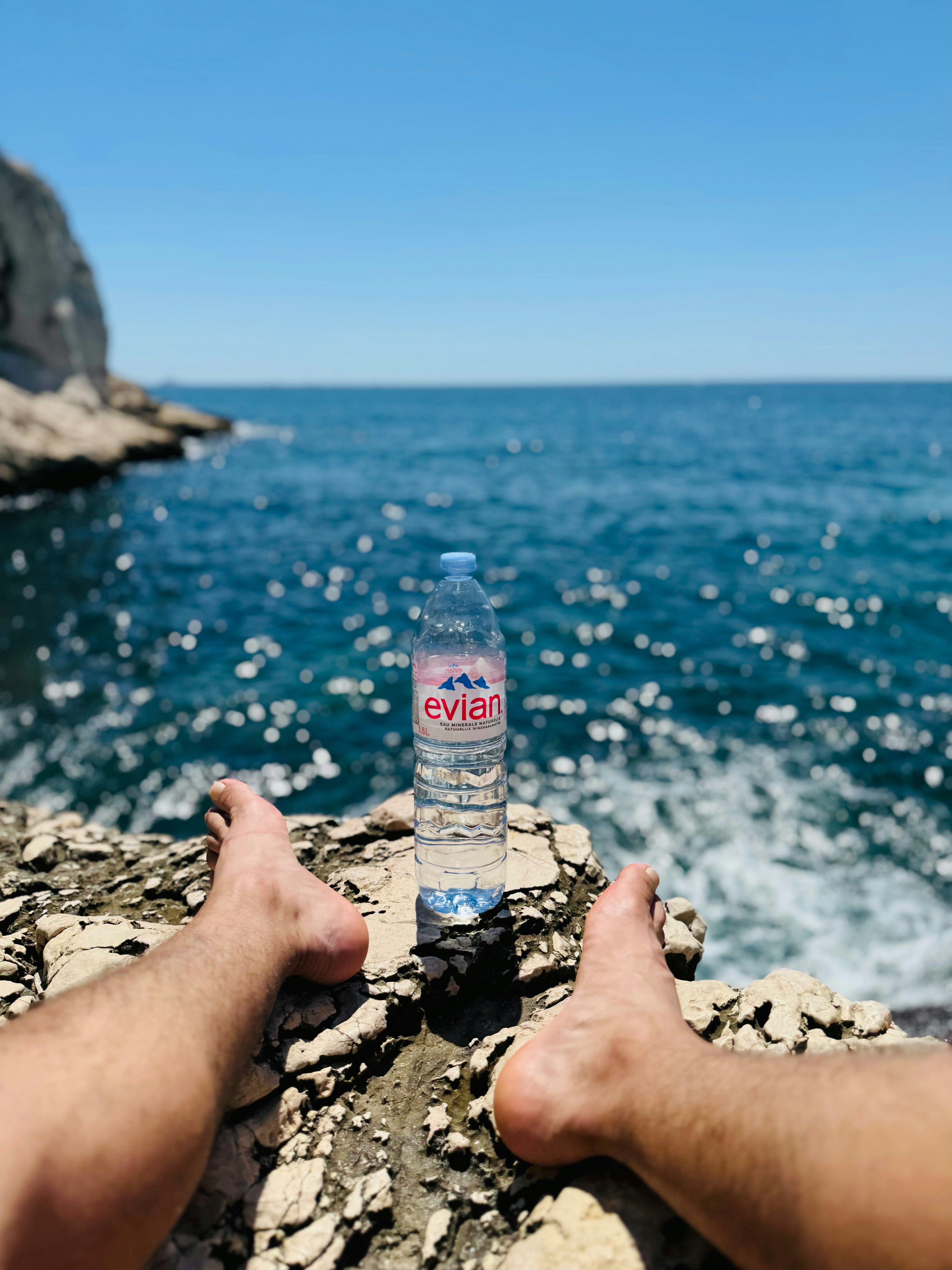 A bottle of water sitting on top of a rock next to the ocean