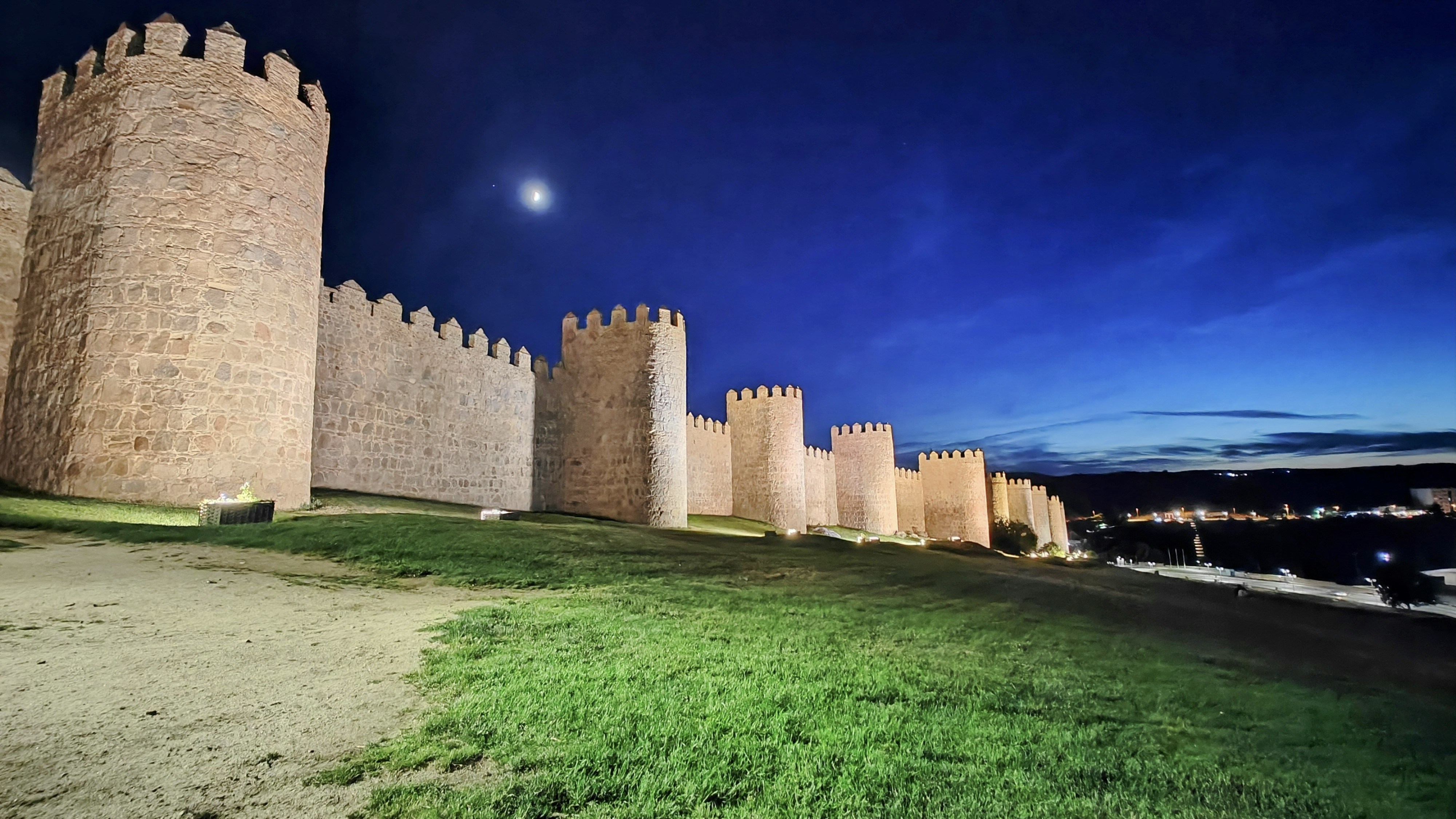 Ancient stone walls at night, dim golden light, dramatic dark sky, atmospheric fog, ancient architecture silhouettes, cinematic mood