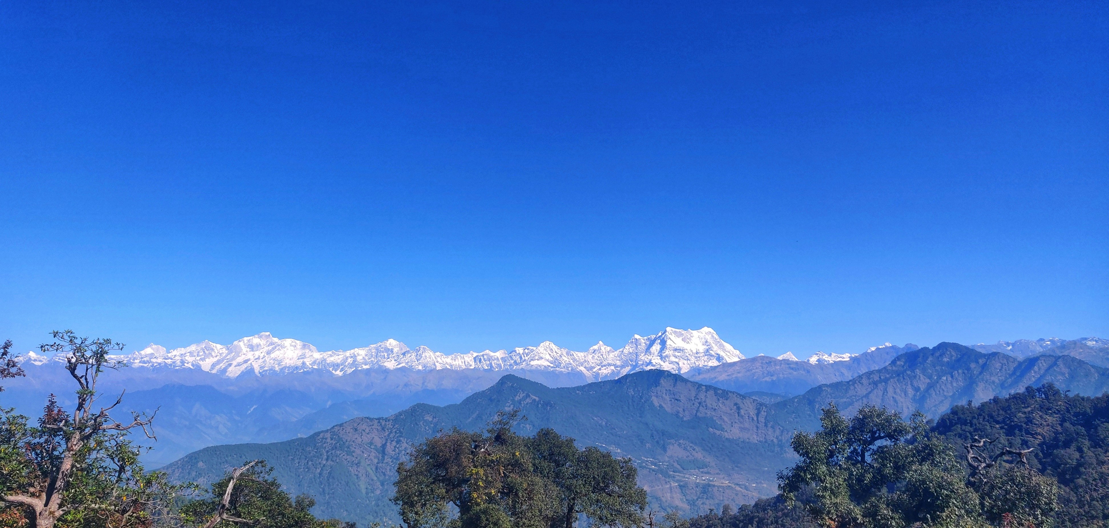 A view of a mountain range with snow capped mountains in the distance