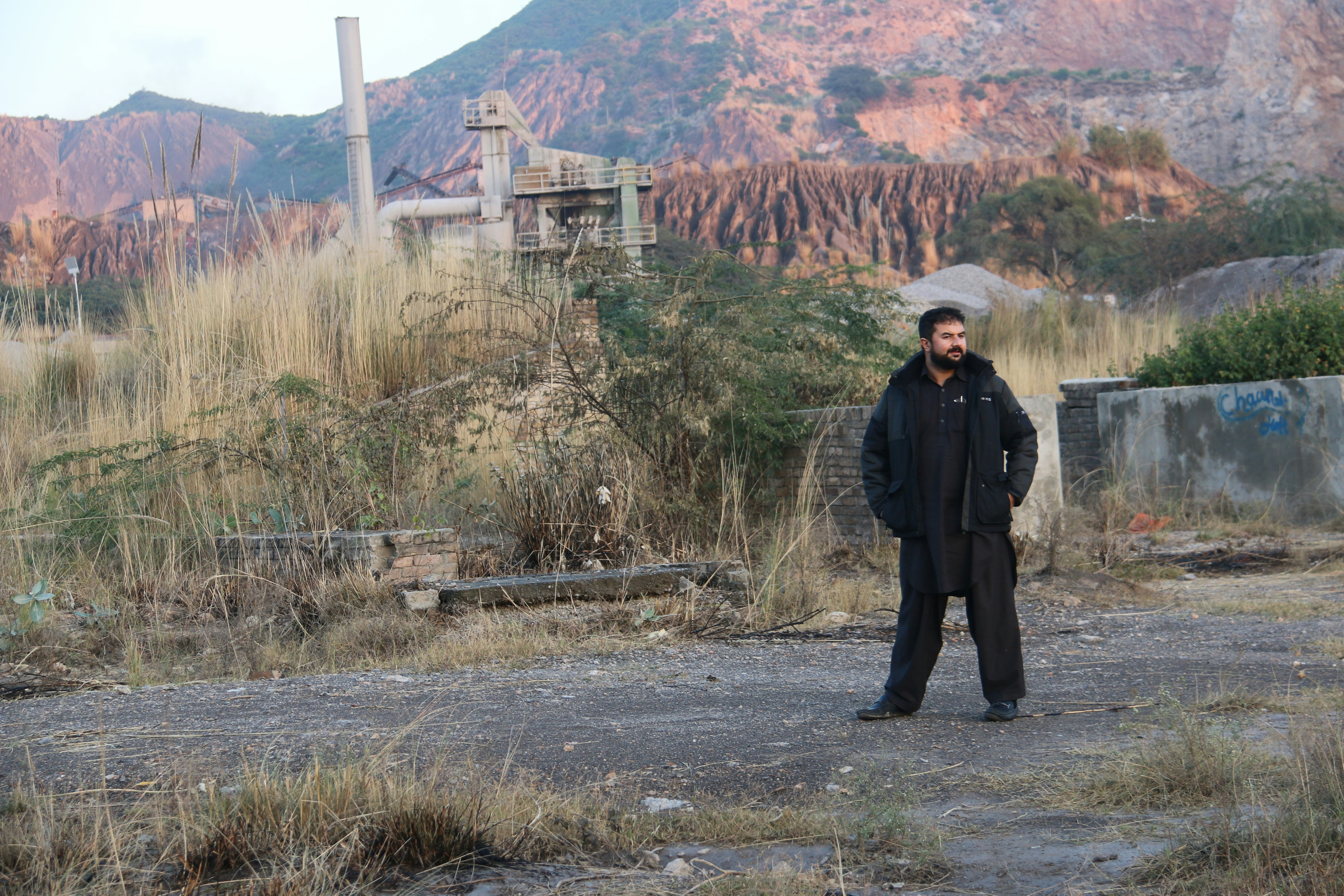 A man standing in a field with mountains in the background