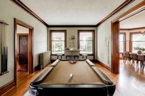 A pool table in a large room with wooden floors