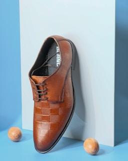 A pair of brown shoes sitting on top of a white box