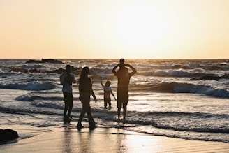 A group of people standing on top of a beach next to the ocean