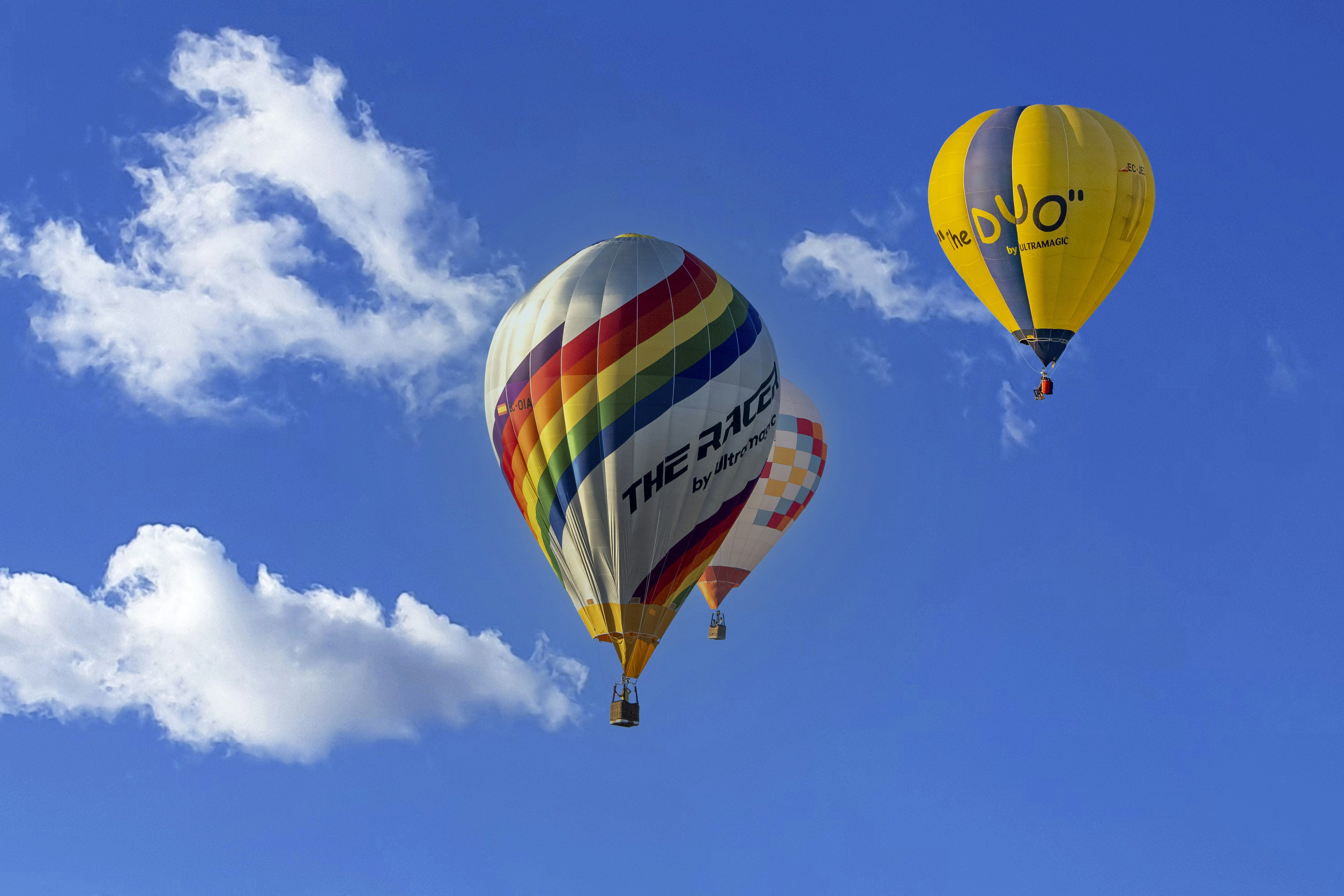 A group of hot air balloons flying through a blue sky