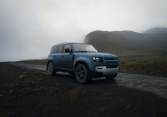 A blue suv driving down a dirt road