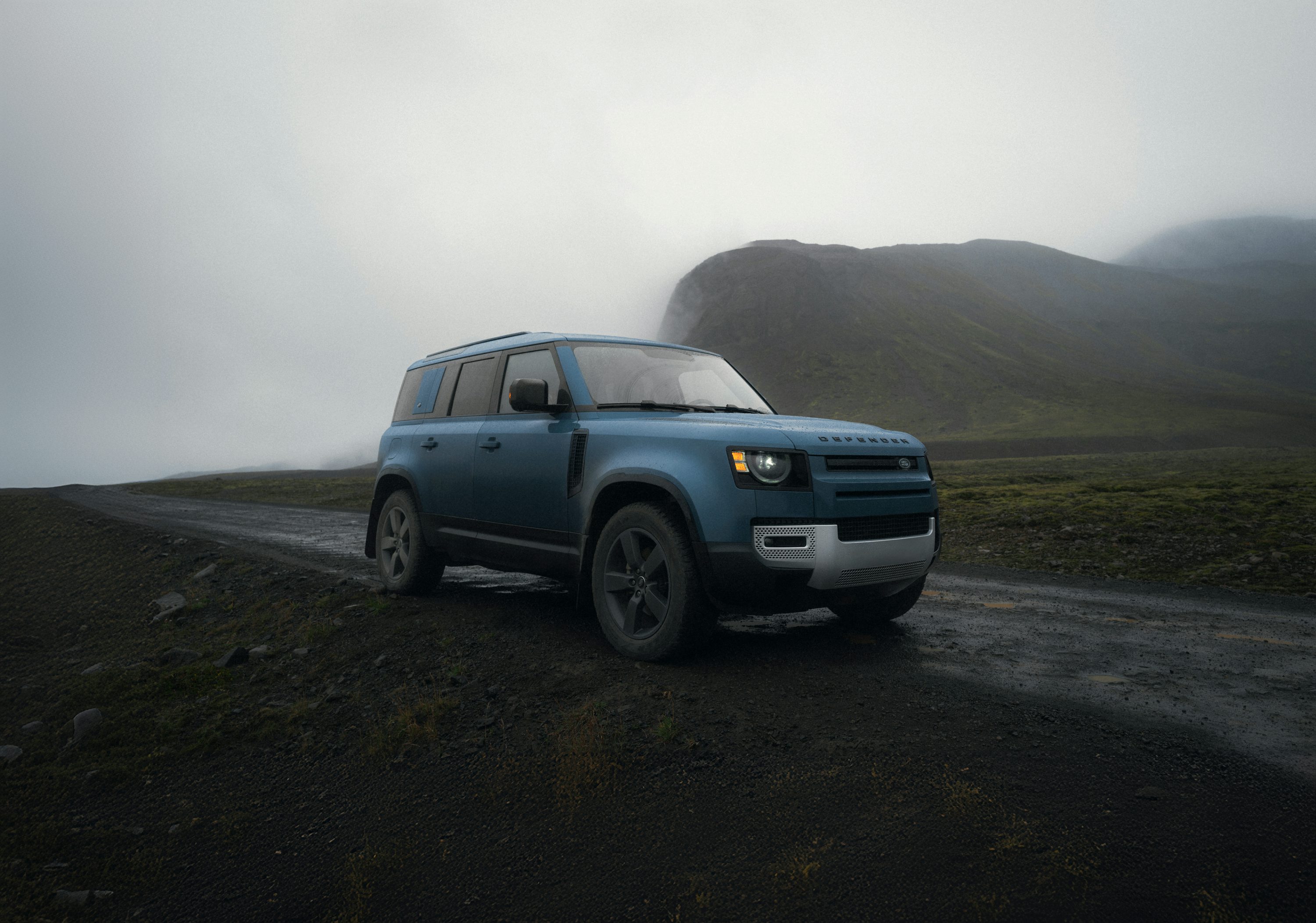 A blue suv driving down a dirt road